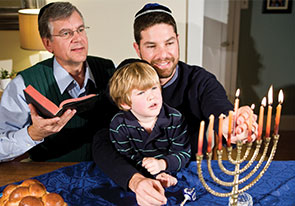 Photo of a family lighting a Menorah. Links to Gifts That Support the Jewish Federation of Broward County